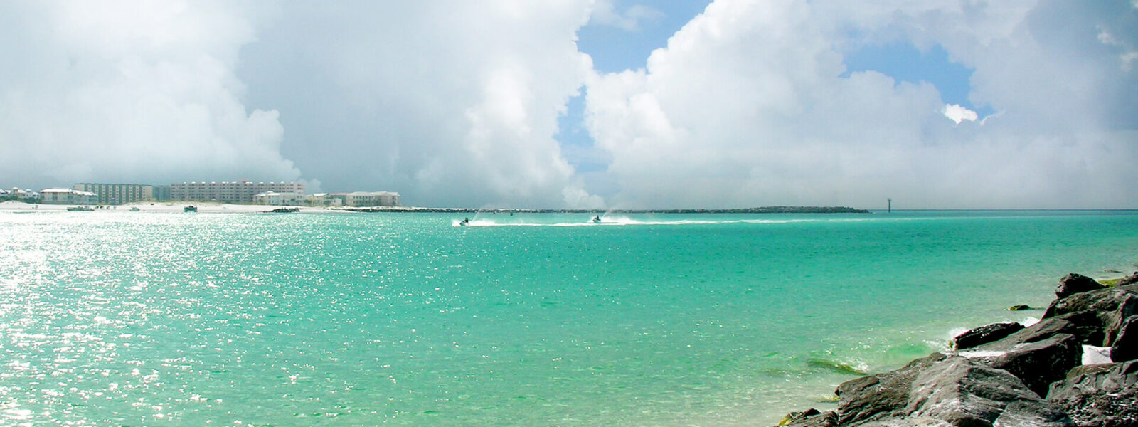 Jet skis skimming emerald water by rocks